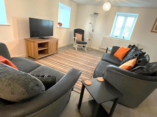 a living room with two couches and a flat screen tv at Stunning Central Alnwick Two Floor Apartment in Alnwick