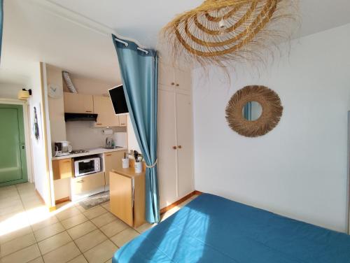 Il comprend un salon avec un lit bleu et une cuisine. dans l'établissement Appartement face mer terrasse couverte parking, au Barcarès