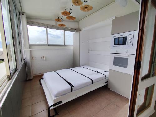 Cette petite chambre comprend un lit et un four micro-ondes. dans l'établissement Appartement face mer terrasse couverte parking, au Barcarès