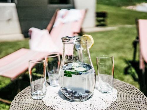 a table with four glasses and a vase with a lemon on it at Apartment Enzian by Interhome in Arriach