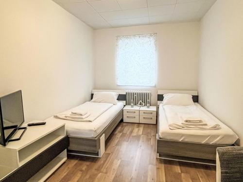two beds in a room with a desk and a tv at Holiday Home Zum munteren Eichhörnchen by Interhome in Dittishausen