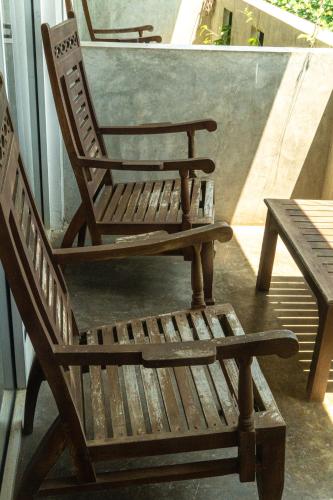 two wooden chairs and a table on a balcony at Cocos in Midigama