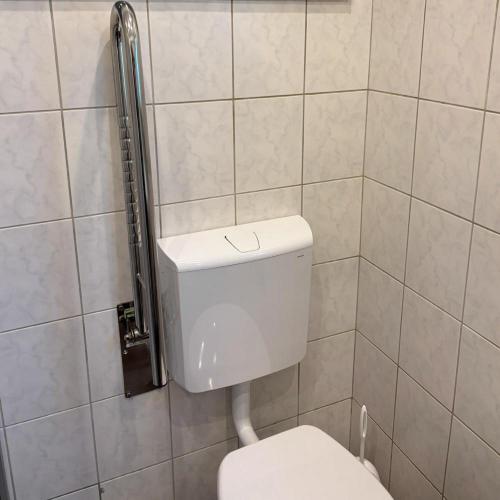 a bathroom with a white toilet in a tiled wall at Ferienhaus – Bergblick am Köterberg in Lügde