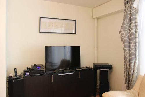 un salon avec une télévision à écran plat assise sur une armoire dans l'établissement Spacious 3 rooms with balcony in Paris, à Paris