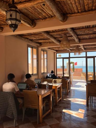 a group of people sitting at a table with laptops at Tasra Surf and Flow in Imsouane