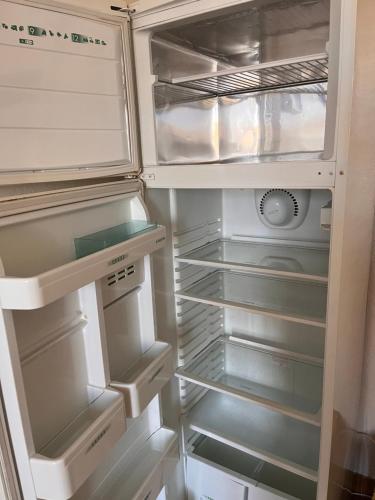 an empty refrigerator with its door open with its door at Maison entre campagne et ville proche Futuroscope in Neuville-de-Poitou