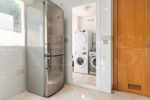 a kitchen with a refrigerator and a washer and dryer at Seaside stay with large terrace, pool & parking REMS in Benalmádena