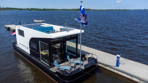 a boat with a flag on a dock in the water at VaarLoft Pur Sang in Offingawier