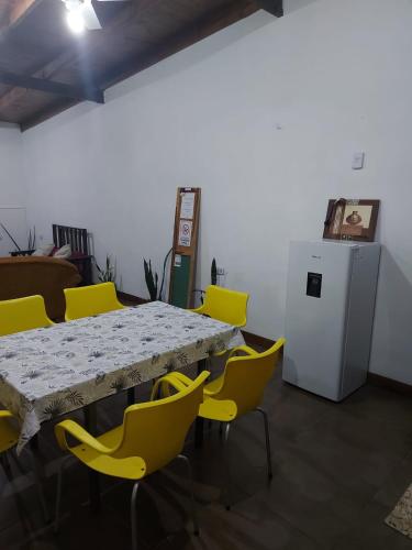 a table with yellow chairs and a white refrigerator at La casa de MaCa in Posadas