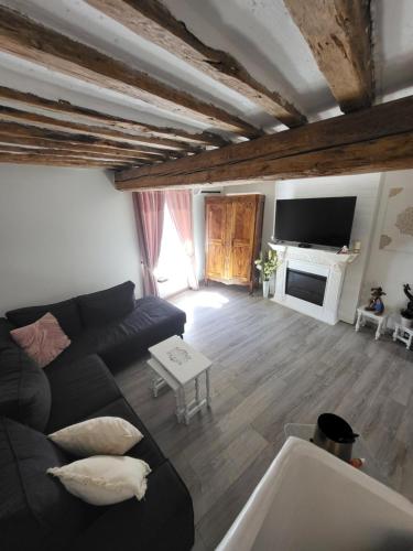 a living room with a black couch and a tv at Duplex en terrasse sur les toits de Provence in Sarrians