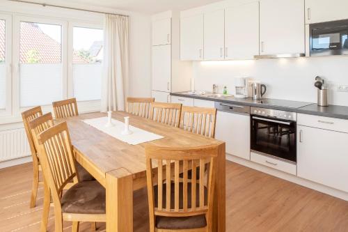 a kitchen with a wooden table and wooden chairs at Ferienhaus DÖRING in Langeoog