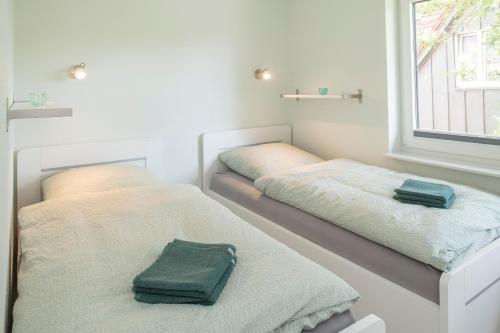 two beds in a room with two green towels at DÜNENGRAS im Beerkutscherhuus in Langeoog