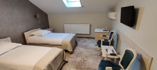 a room with two beds and chairs and a tv at Hotel Coroana in Tîrgu Frumos