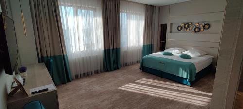 a bedroom with a bed with a green blanket at Hotel Coroana in Tîrgu Frumos