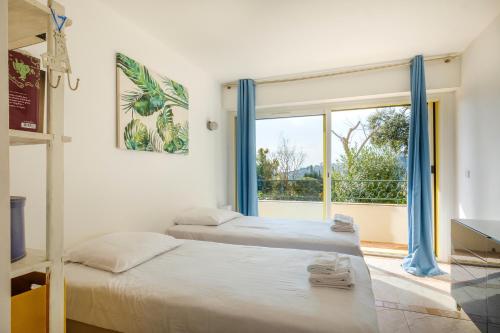 deux lits dans une chambre avec une grande fenêtre dans l'établissement Duplex 2 chambres Golden Sun, à Théoule-sur-Mer