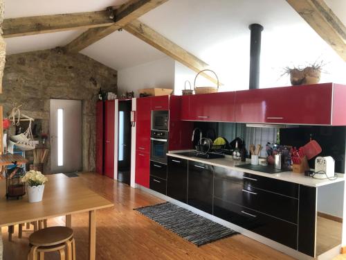 a kitchen with red cabinets and a wooden table at Casa do Couço in Sever do Vouga