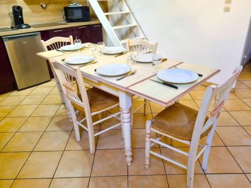 a wooden table with chairs and plates on it at Pacy sur Eure loft en plein centre in Pacy-sur-Eure