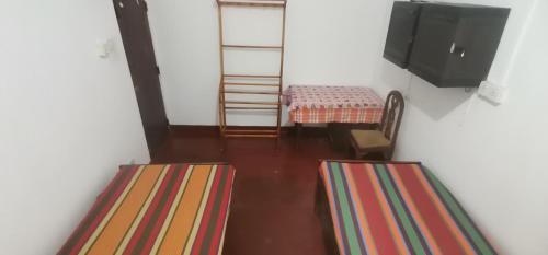 a room with two beds and a tv and stairs at Hostel 42 in Hikkaduwa