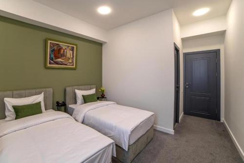 two beds in a room with green walls at Benefice Hotel Yerevan-通緝 in Yerevan