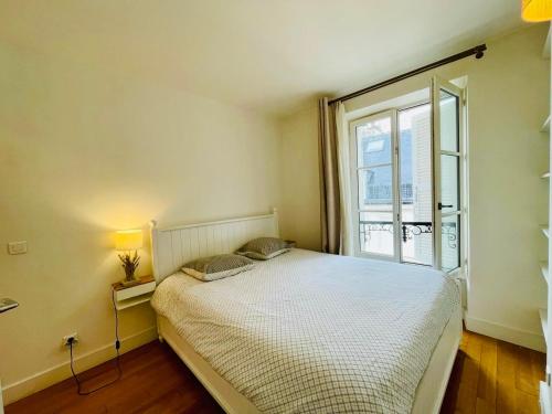 une chambre avec un lit et une grande fenêtre dans l'établissement Tour Eiffel Invalides Pierre Leroux, à Paris