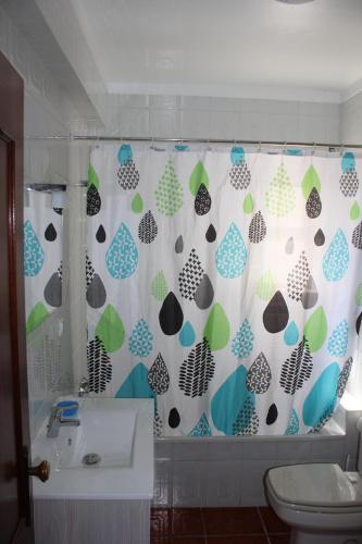 a bathroom with a shower curtain with a toilet and a sink at Baleal Holiday Apartment in Baleal