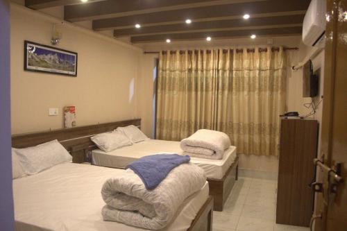 Una habitación con dos camas y un televisor. en Hotel Resunga & Thakali Kitchen, en Bhaktapur