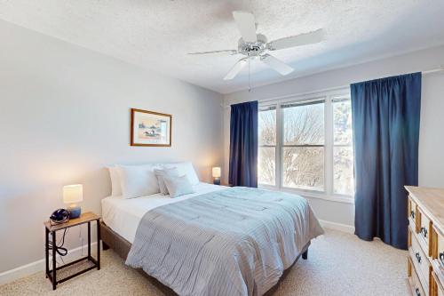 a bedroom with a bed and a window with blue curtains at Northern Michigan Manistee Magic in Manistee