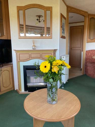 Un jarrón de flores amarillas sobre una mesa. en Craigmore Caravan, en Coleraine
