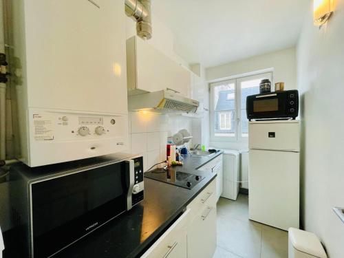 une cuisine avec des appareils blancs et un comptoir noir dans l'établissement Tour Eiffel Invalides Pierre Leroux, à Paris