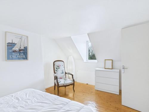 - une chambre avec un lit, une chaise et une commode dans l'établissement Maison en pierre avec grand jardin pour 4, à Plouguerneau