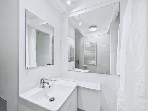 une salle de bain blanche avec un lavabo et un miroir dans l'établissement Maison en pierre avec grand jardin pour 4, à Plouguerneau