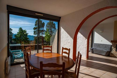 a dining room with a table and a large window at Village de vacances Le Serre de la Can in Saint-Germain-de-Calberte