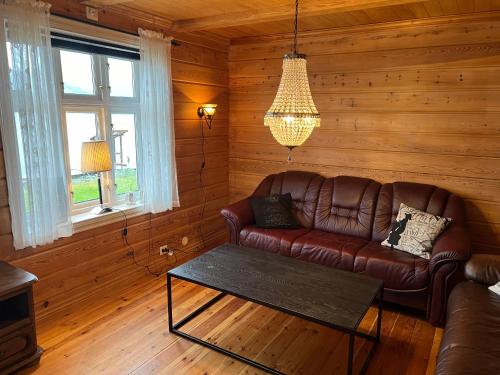 a living room with a leather couch and a table at Sjarmerende feriehus med privat brygge in Leikanger
