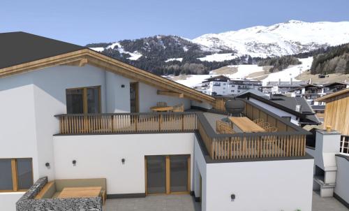 a house with a balcony with mountains in the background at Aparthotel Fernblick in Fiss
