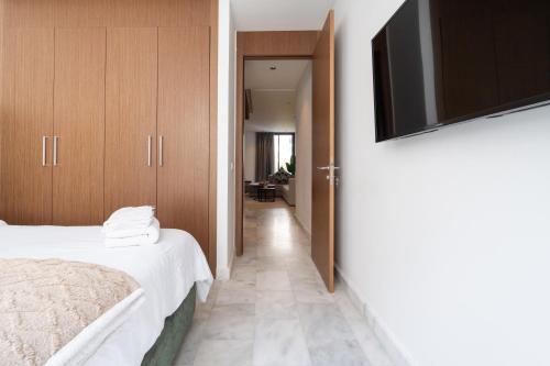 a bedroom with a bed and a flat screen tv at Studio Ferme Bretonne, Bien Desservi & Salle Gym in LʼOasis