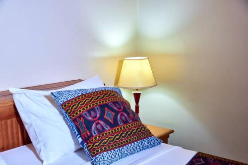 a bed with a pillow and a lamp on it at CONGRESS HOTEL Yaoundé in Yaoundé