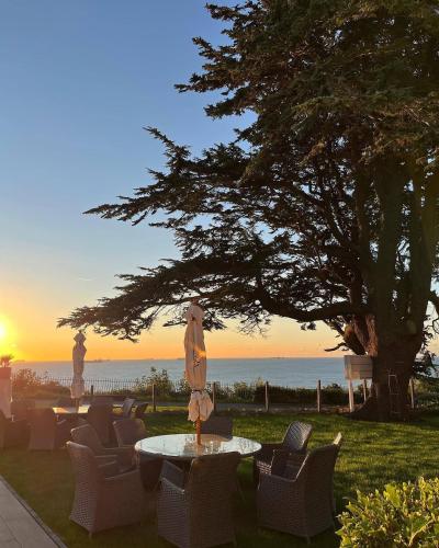 eine Terrasse mit Stühlen und einem Tisch mit Blick auf den Sonnenuntergang im Hintergrund in der Unterkunft The Brunswick in Shanklin