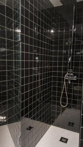 a black tiled bathroom with a shower with a glass door at Flat with garage and balcony with view to a garden in Vila Nova de Gaia