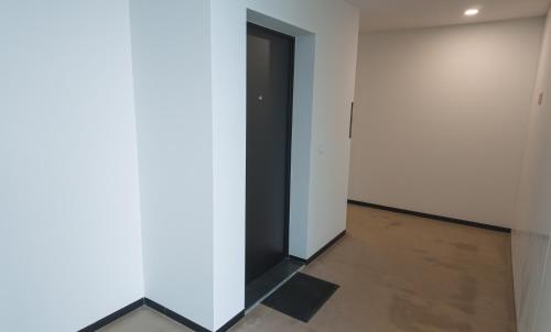 a hallway with a black door and a white wall at Flat with garage and balcony with view to a garden in Vila Nova de Gaia