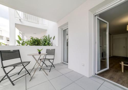 Cet appartement blanc dispose d'un balcon avec une table et des chaises. dans l'établissement Résidence de Cannes La Bocca, à Cannes