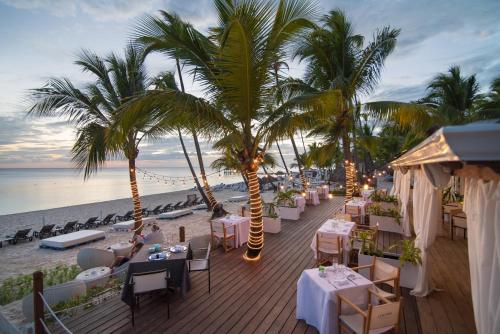 a restaurant on the beach with tables and palm trees at Catalonia Bayahibe - All Inclusive in Bayahibe