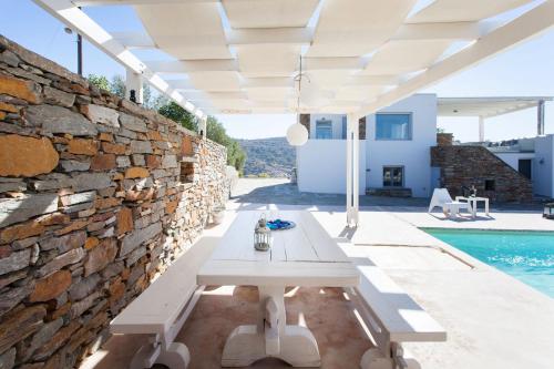 a patio with a table and a stone wall at Kea Villa Thea by A&D Properties in Otzias
