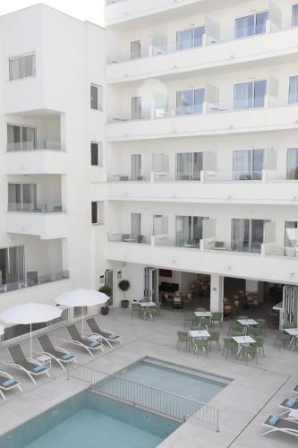 apartamentowiec z basenem, stołami i krzesłami w obiekcie Aparthotel Marina Drach w Porto Cristo