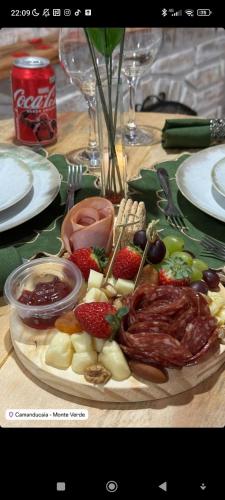 a plate of food with meat and fruit on a table at Pousada rota nas montanhas in Camanducaia