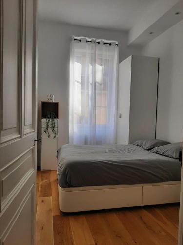 une chambre avec un grand lit et une fenêtre dans l'établissement Haussmannien rénové et climatisé, Centre de Lyon, à Lyon