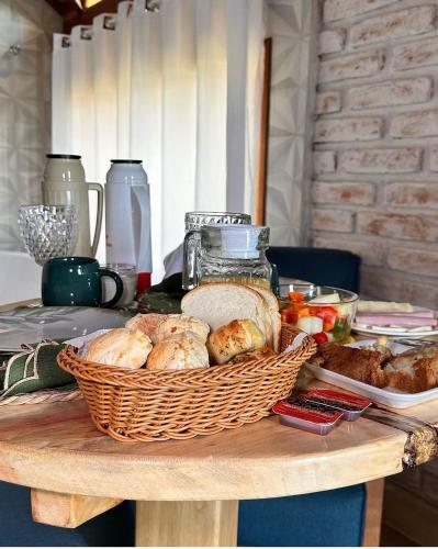 a table with a basket of bread and vegetables on it at Pousada rota nas montanhas in Camanducaia
