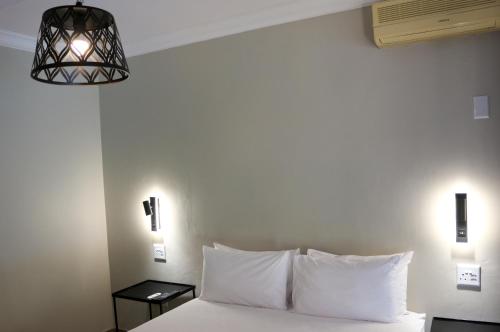 a bedroom with a bed with white pillows and a lamp at Luxury Heights Bed and Breakfast in Newcastle