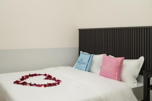 a white bed with pillows and a flower wreath on it at Luma Signature Hotel in Seremban