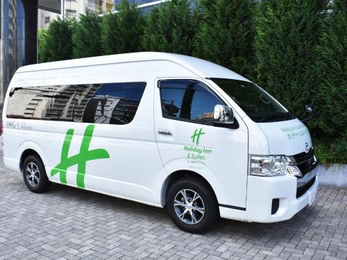 大阪市にあるホリデイ・イン＆スイーツ新大阪の側面に緑色の文字が書かれた白いバン