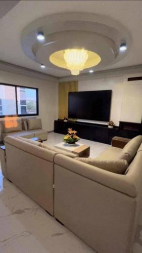 a living room with a large couch and a flat screen tv at Couple - Private Jacuzzi Pool in Mabalacat